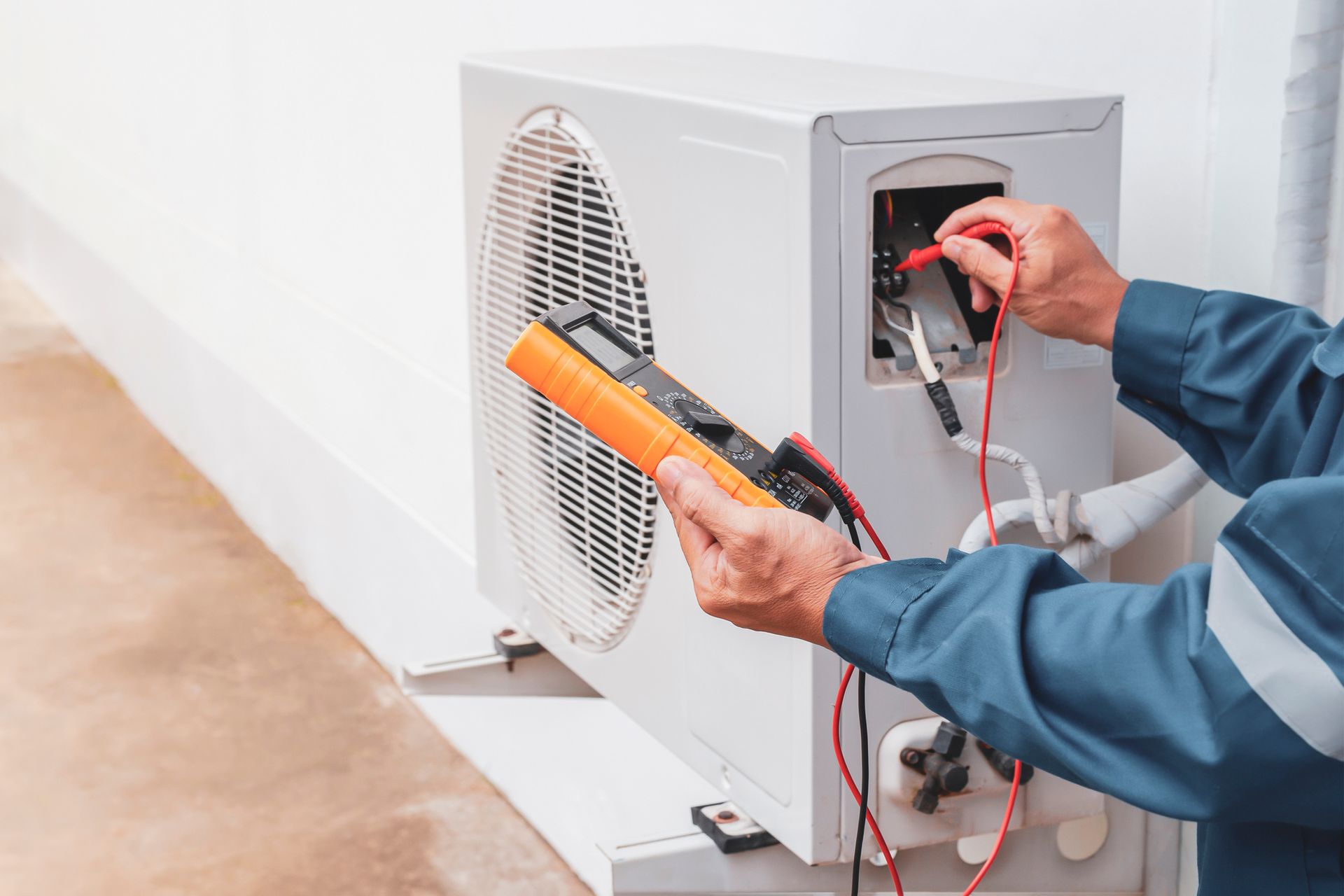 A Ready Energy Solutions Technician is fixing an air conditioner with a multimeter.