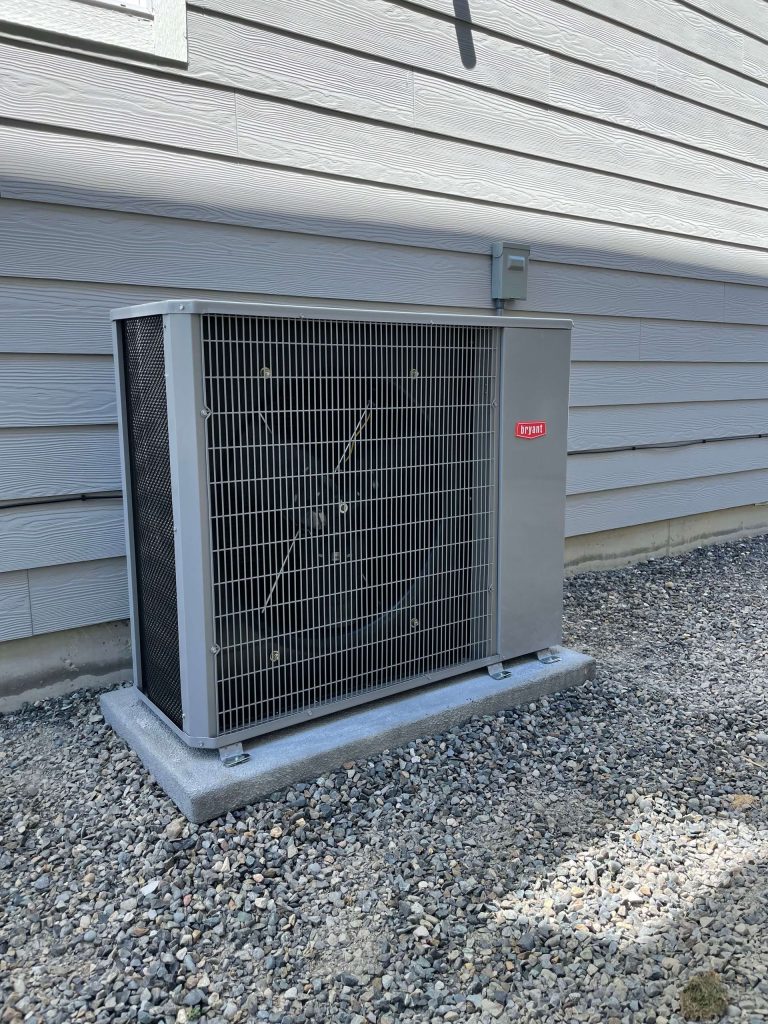 A large air conditioner is sitting outside of a house.
