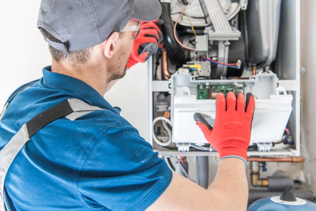 Technician replacing furnace filter and checking a thermostat and CO detector in a Seattle home.