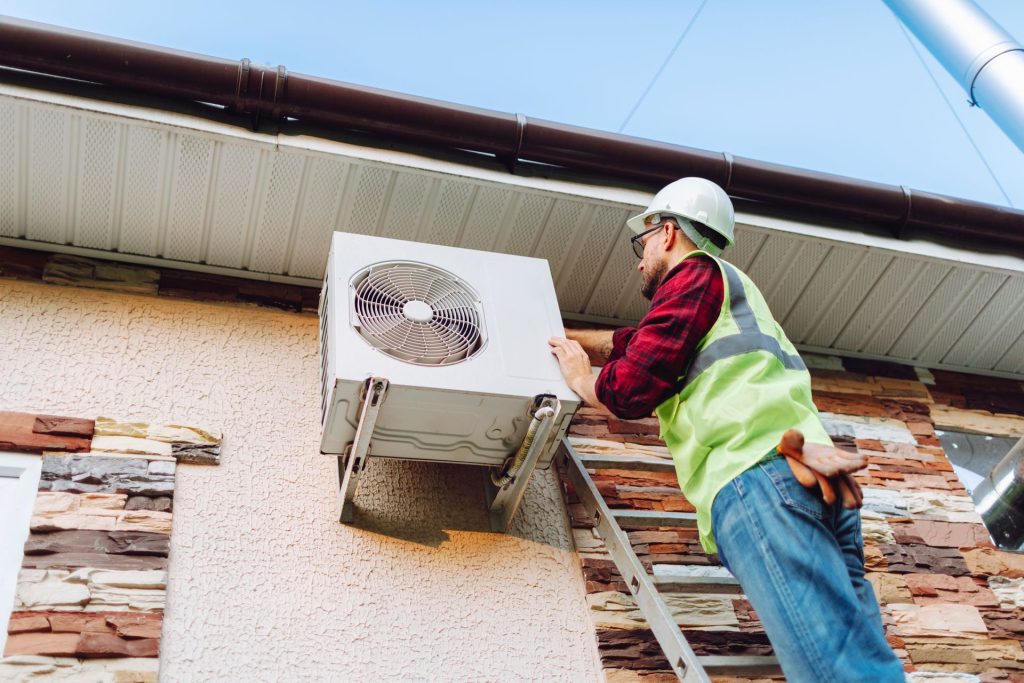 Technician checking a heat pump outside a Seattle home during winter maintenance.