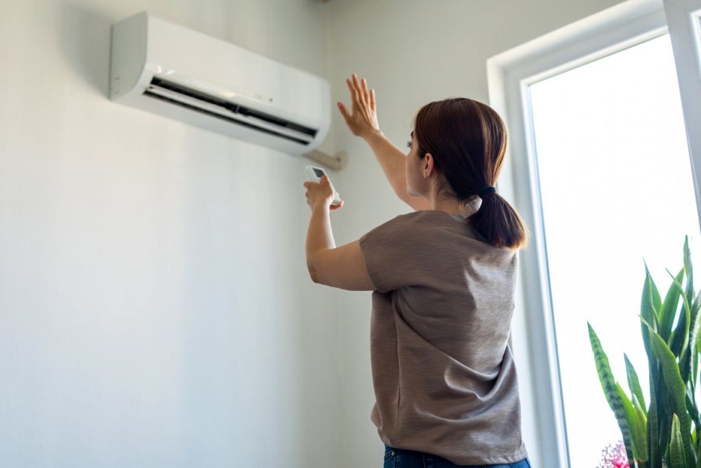 HVAC technician performing late summer maintenance on an outdoor unit in Seattle, WA.