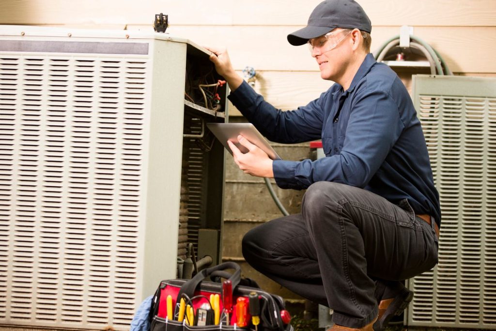 HVAC technician installing a central air conditioning system outside a Seattle home during summer.