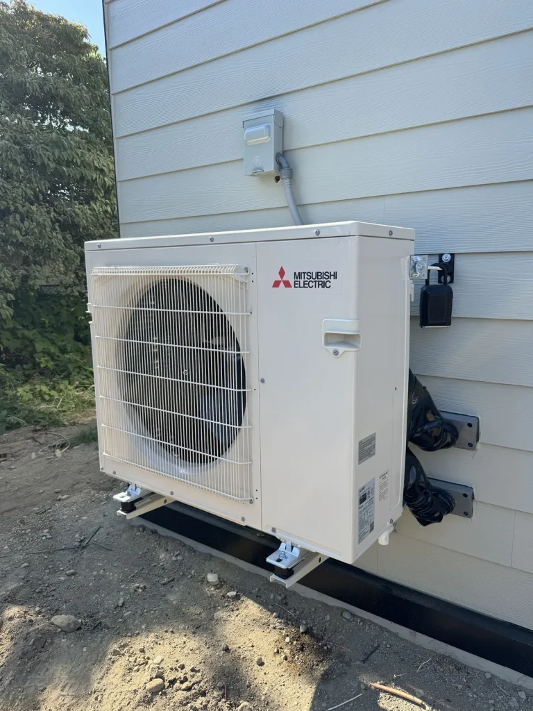 Mitsubishi Electric heat pump installed beside white siding