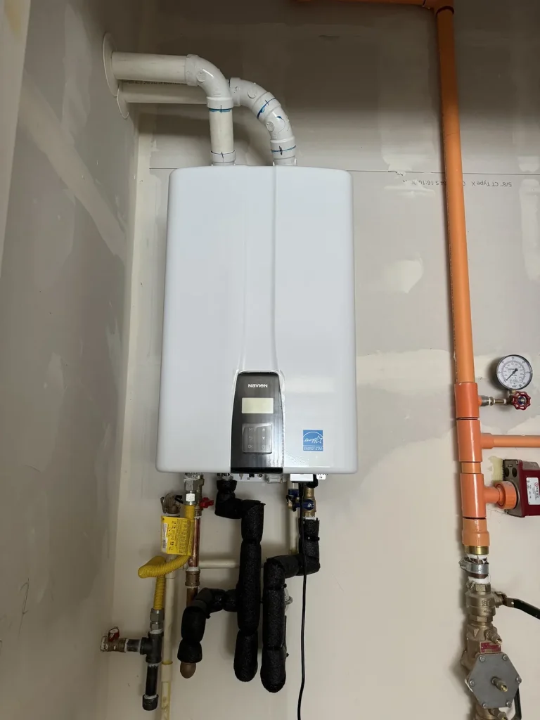 Wall-mounted tankless water heater with copper supply piping and a pressure gauge